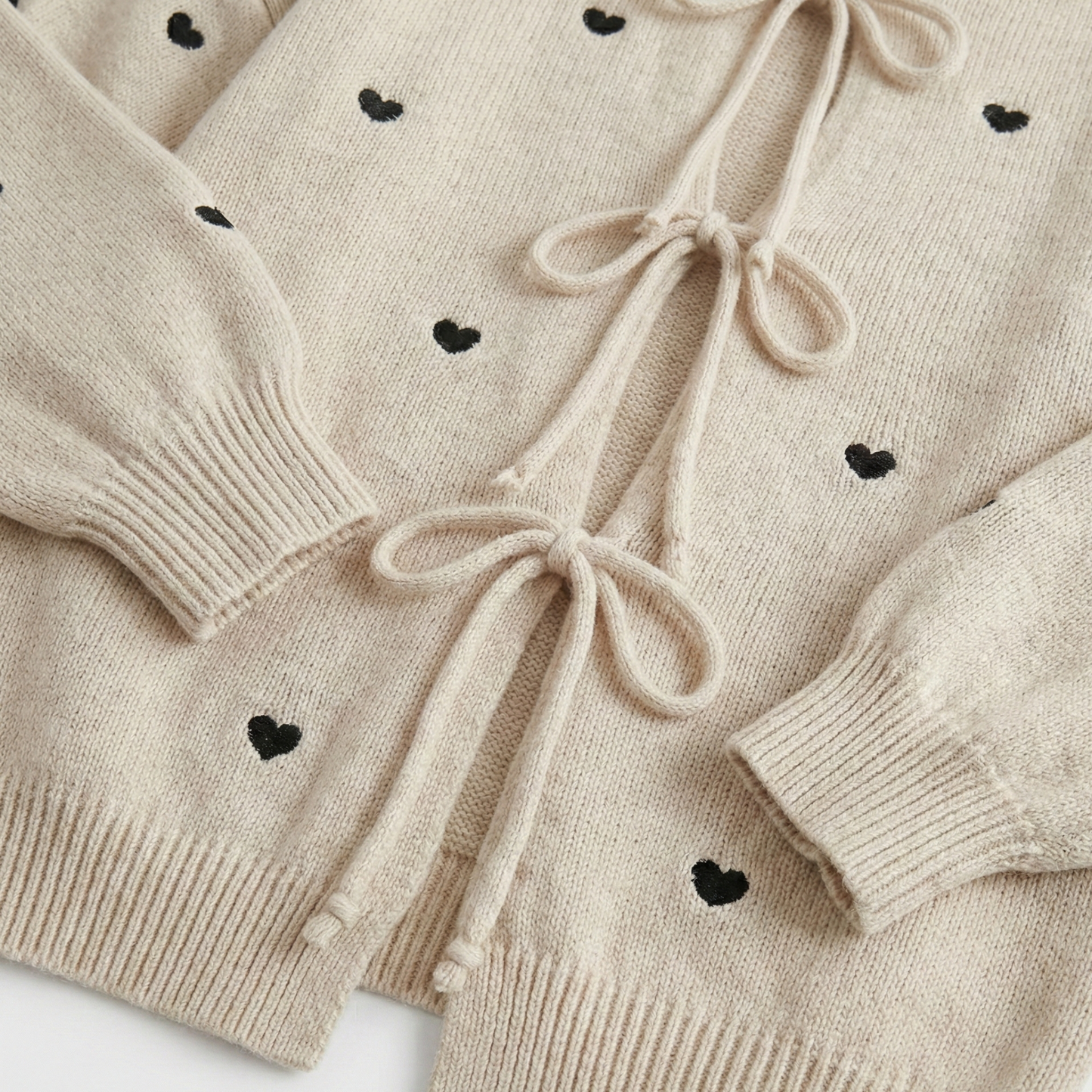 Knit cardigan with small black heart pattern and three front tie bows