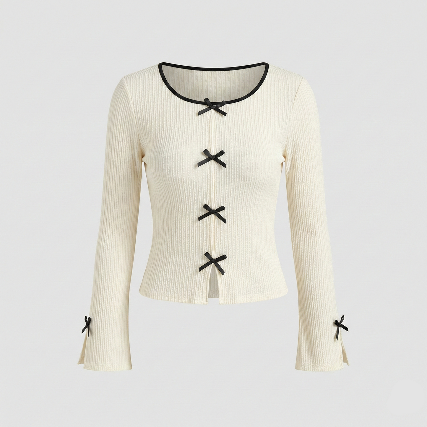 Ivory ribbed knit long-sleeve top featuring small black decorative bows down the center and on the sleeve cuffs.