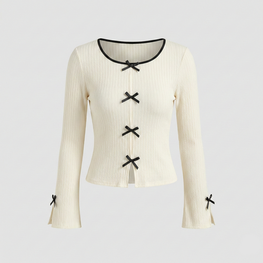 Ivory ribbed knit long-sleeve top featuring small black decorative bows down the center and on the sleeve cuffs.