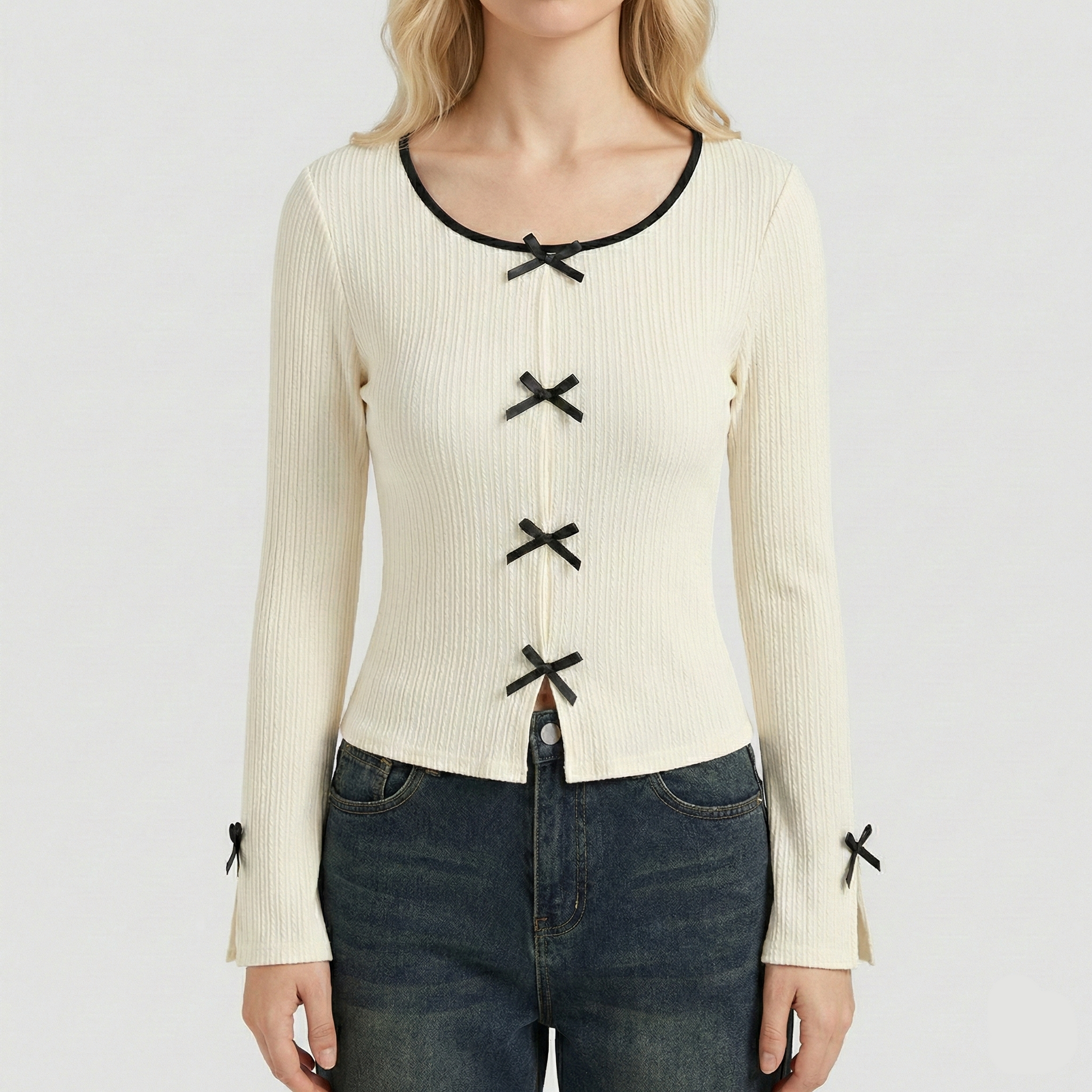Ivory ribbed knit long-sleeve top featuring small black decorative bows down the center and on the sleeve cuffs.
